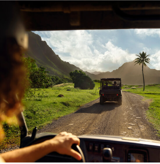 A traveler sits on the ground in front of a mountain view.