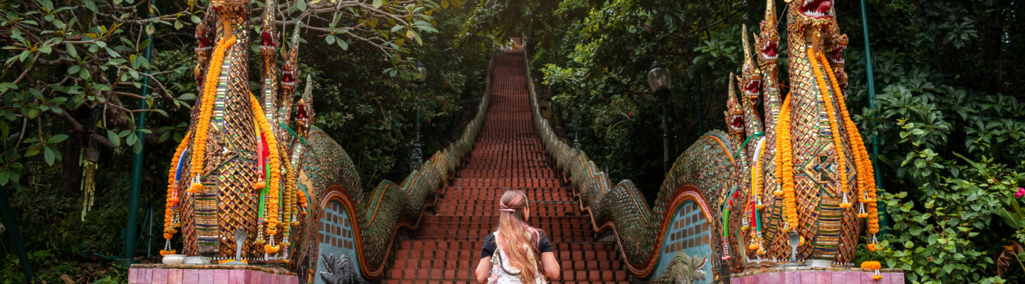 Una viajera sube las ornamentadas escaleras del templo Doi Suthep en Tailandia.